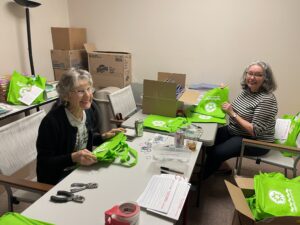 volunteers at a table with green bags
